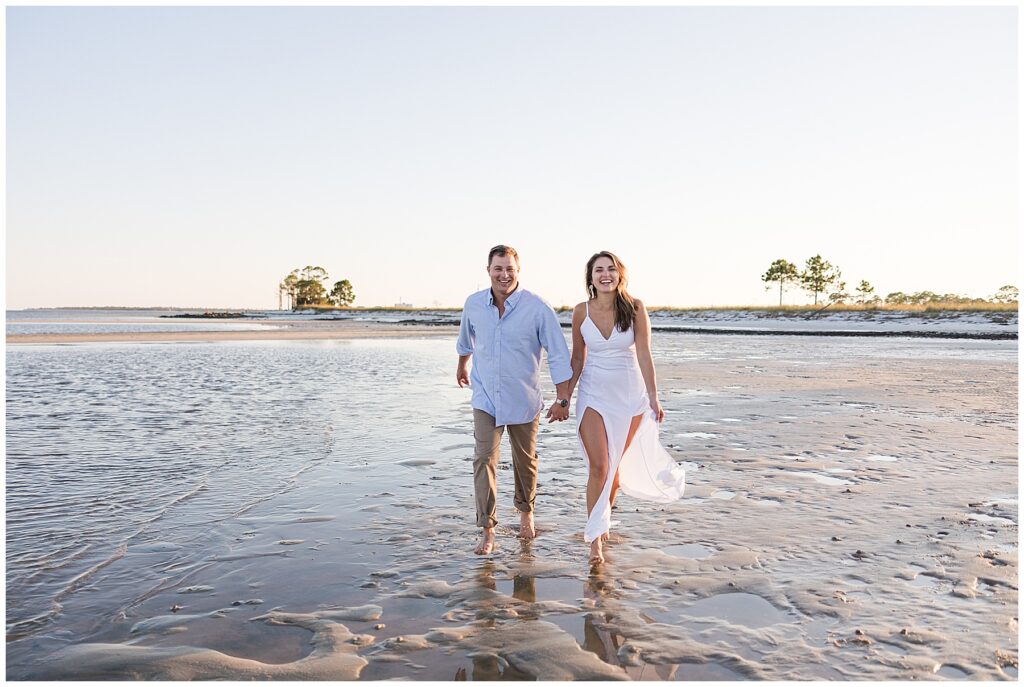 Engaged couple in new outfits posing in coastal grasses at Mashes Sands Beach, captured by Tallahassee engagement photographer