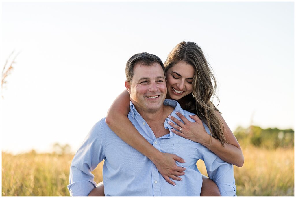 Backlit portrait of engaged couple with golden sun flare shining behind them at Mashes Sands Beach near Tallahassee