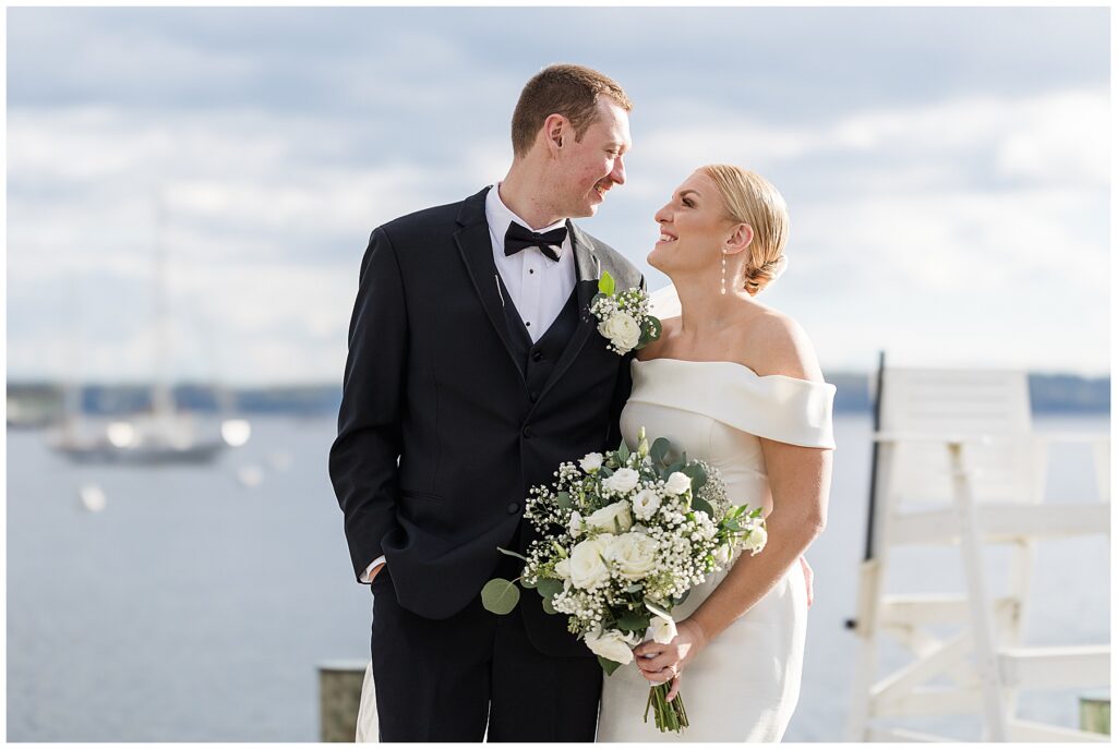 Bride and groom standing by the water during portraits at their coastal Florida wedding.