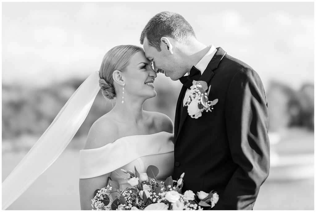 Bride and groom holding hands during waterfront portraits at their Florida coastal wedding.