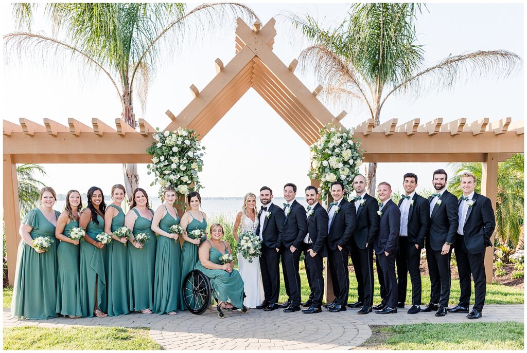 Full bridal party standing at the altar with palm trees and water backdrop during North Florida coastal wedding