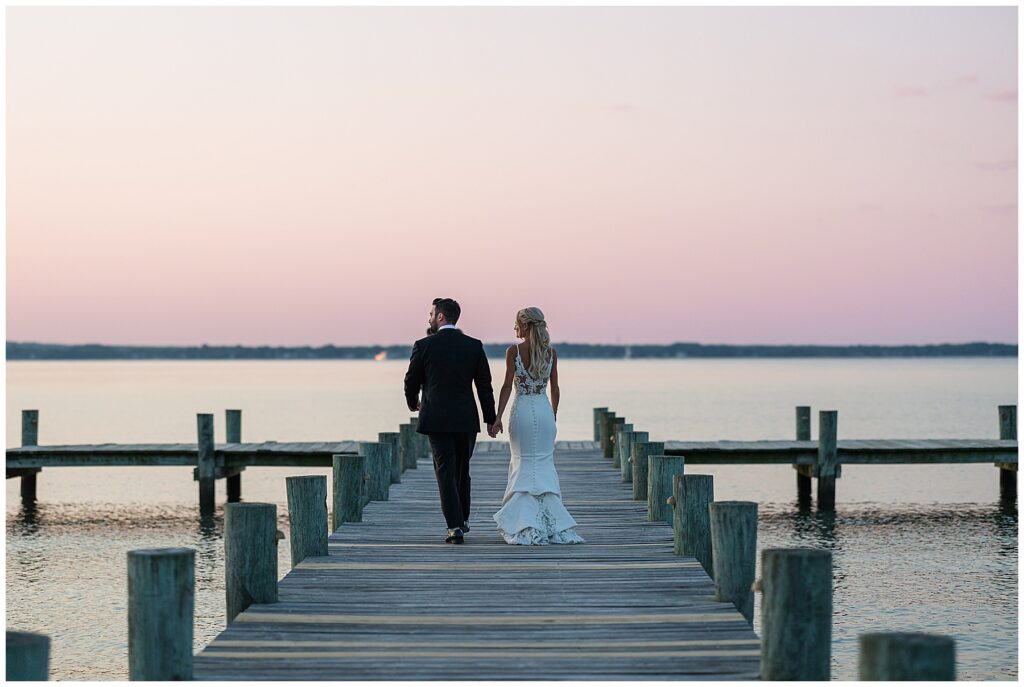 Couple walking hand in hand on dock during sunset portraits by the water in North Florida