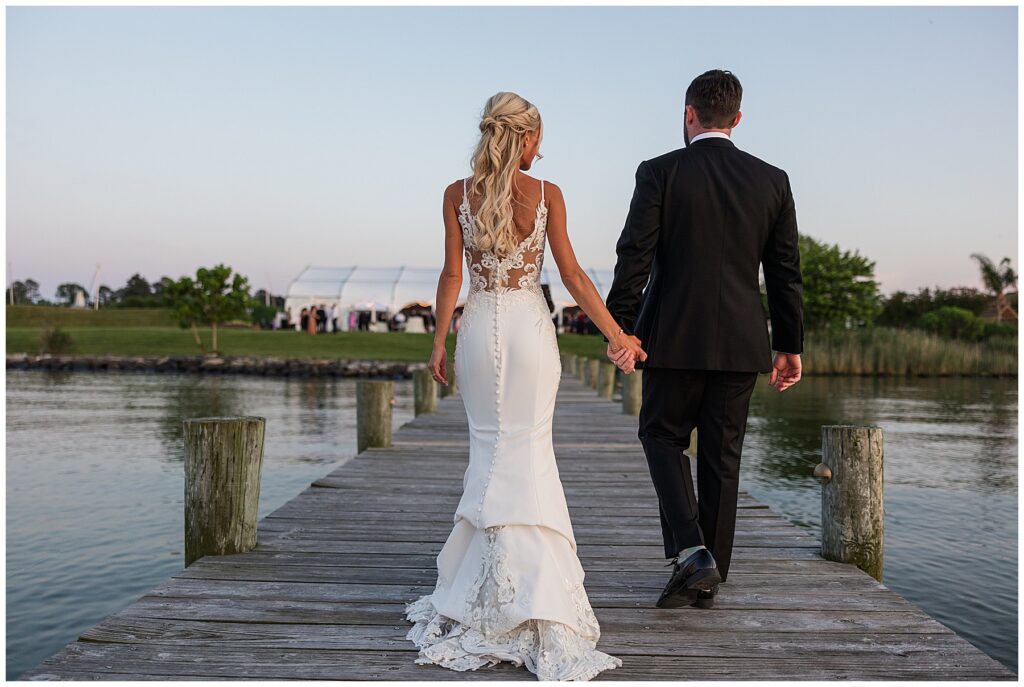 Romantic silhouette of bride and groom on dock with colorful sunset sky over the ocean in North Florida