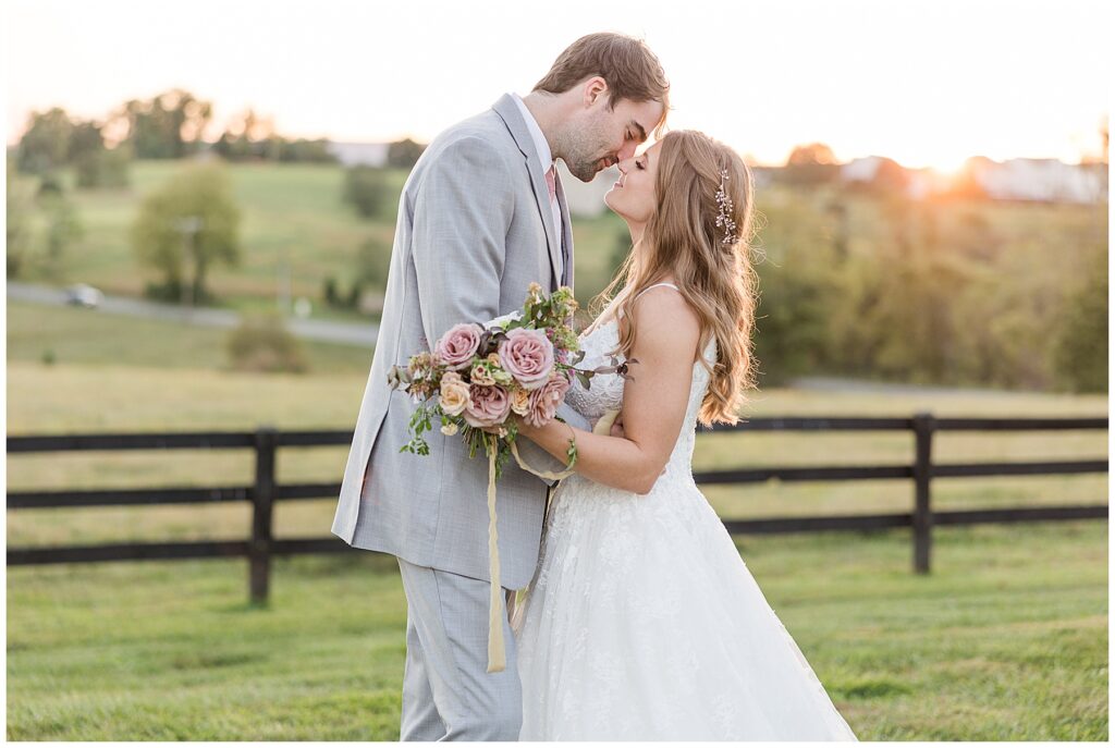 Bride and groom embrace during golden hour at their barn wedding in North Florida, showcasing her lace gown, bouquet, and wedding ring.
