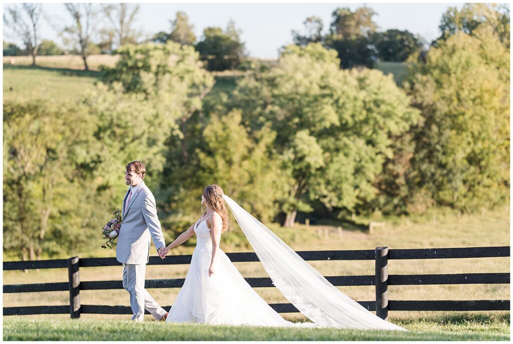 Bride rests her head on groom’s shoulder while holding a bouquet of mauve roses during their barn wedding portraits.