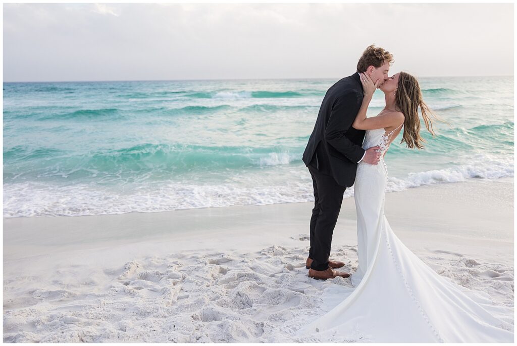 Couple kissing as waves roll in behind them on Santa Rosa Beach.