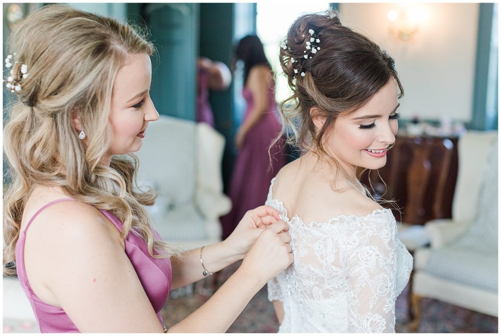 The maid of honor helps the bride get into her wedding dress | Taylor'd Southern Events