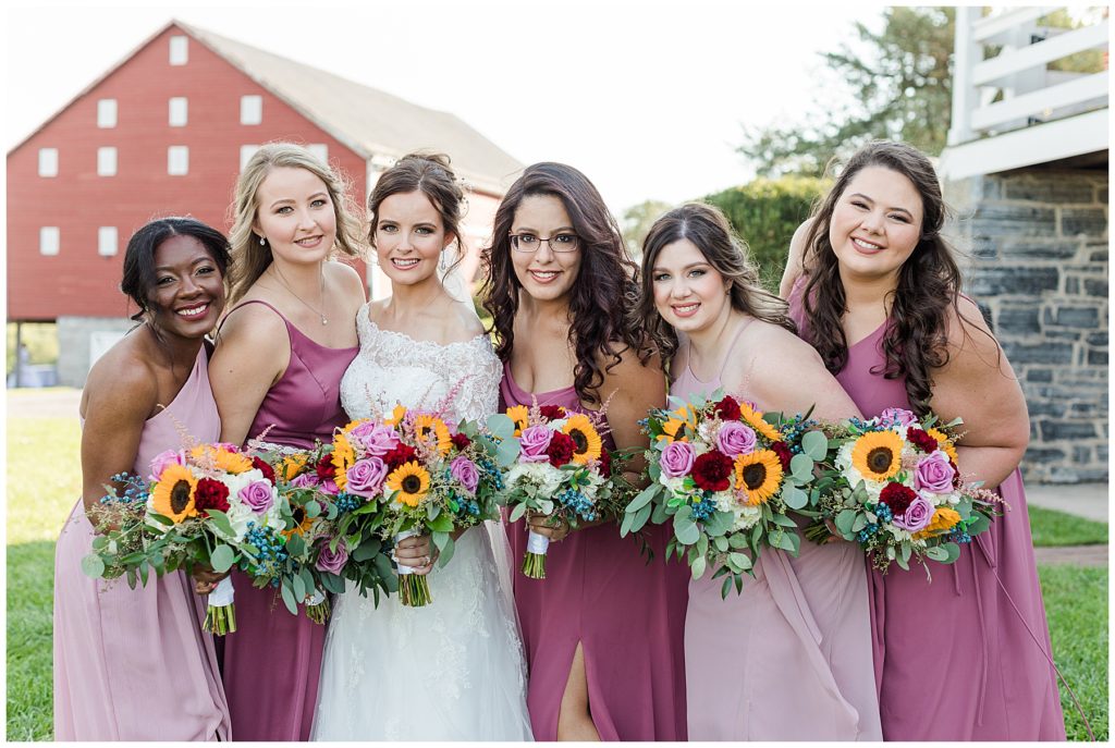 The bride with her bridesmaids in different shades of pink dresses with pink and yellow bouquets | Taylor'd Southern Events | Maryland Wedding Photographer